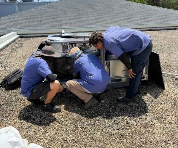 Two Value Air and Heat technicians servicing a rooftop HVAC unit